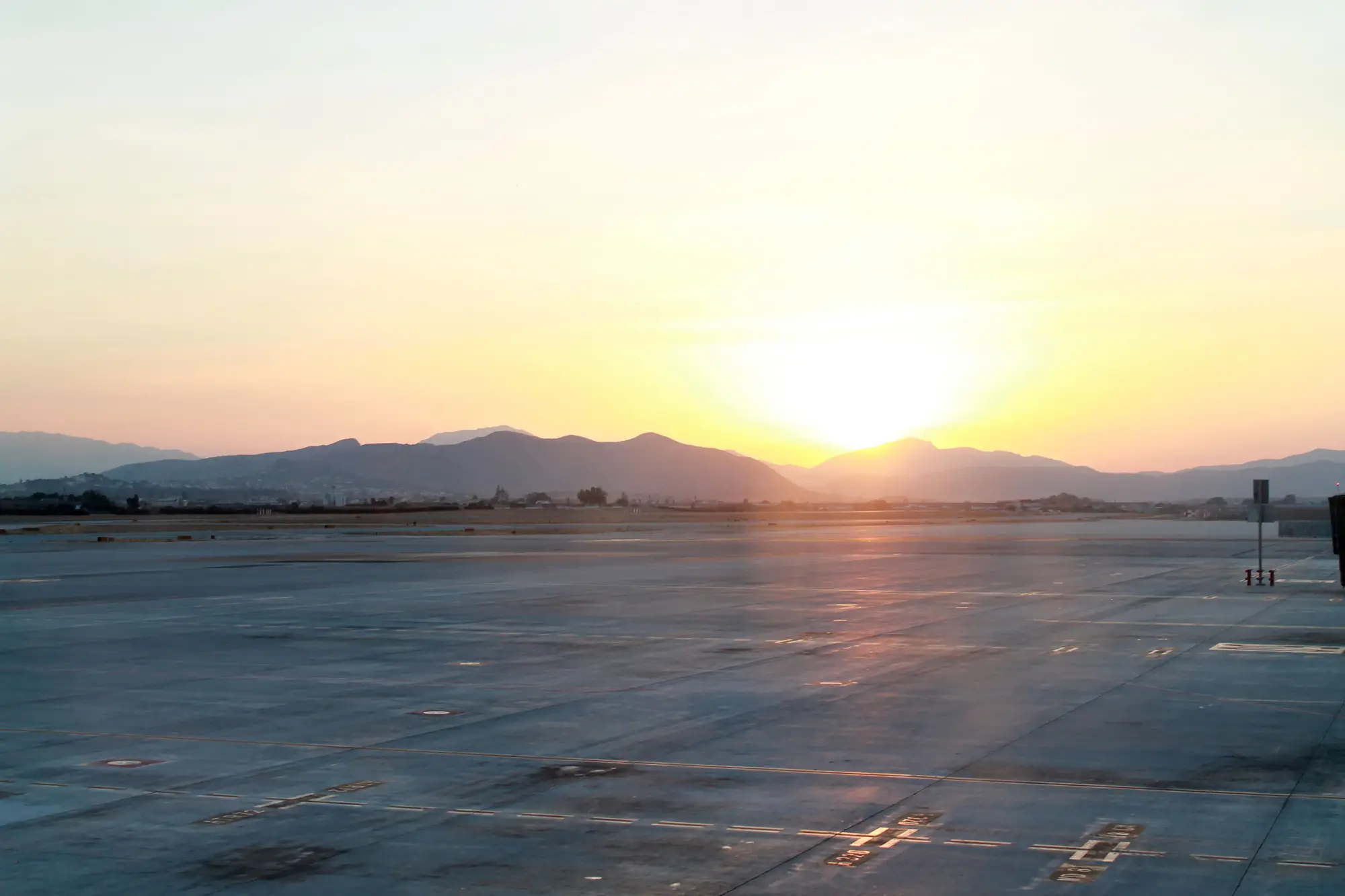 An airport apron at sunrise, mountains on the horizon